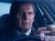 close up middle aged man in a suit with a hand handing him a coffee cup through the driver's side window